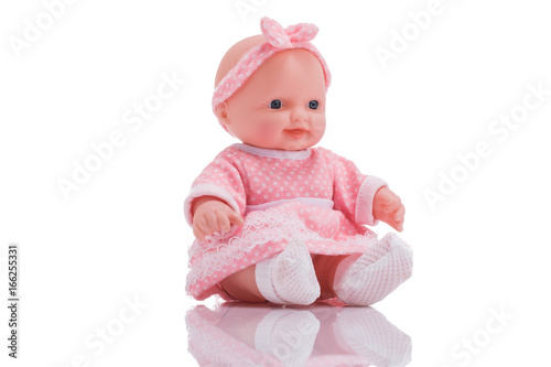 Cute little plastic baby doll with blue eyes sitting isolated on white background