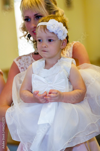 Obraz na płótnie baby. cute little girl is listening to priest at christening ceremony in church w salonie