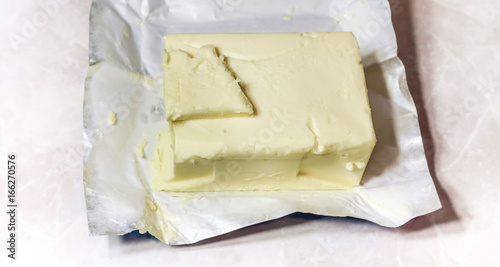 Creamy butter in its unwrapped foil paper. Isolated on light table photo