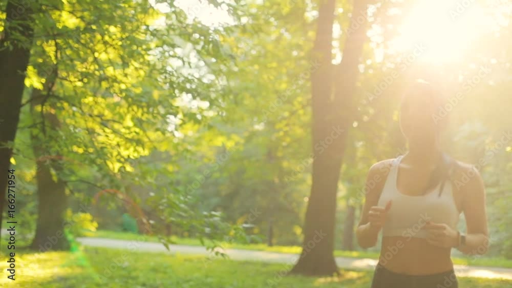Handsome woman runing through the park in the morning during sunrise.