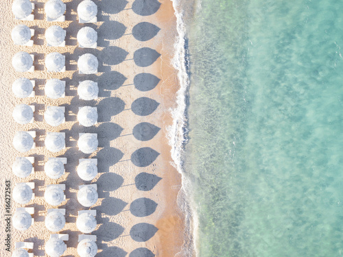 Obraz na płótnie View from above, stunning aerial view of an amazing empty white beach with white beach umbrellas and turquoise clear water during the sunset. Mediterranean sea, Sardinia, Italy. w salonie
