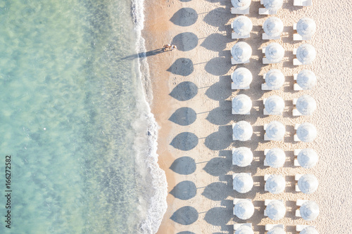 Aerial view of white beach, umbrellas and turquoise clear water during sunset, Mediterranean sea, Sardinia, Italy,