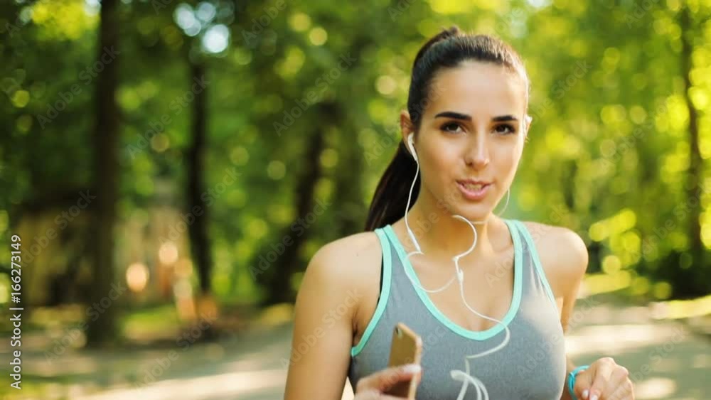 Portrait of handsome woman runing through the park in the morning during sunrise and looking stright to the camera. Portrait of handsome woman runing through the park in the morning during sunrise and looking stright to the camera.