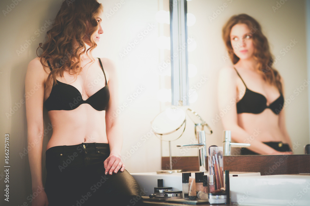 Young woman looking herself in the mirror on bathroom. Young woman looking herself in the mirror on bathroom.
