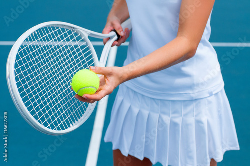 Tennis player holding tennis racket and ball in hand  on the tennis court © Dmytro Flisak
