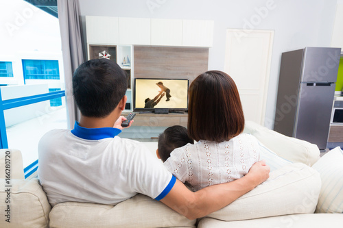 Happy family watches television while sitting on the sofa.