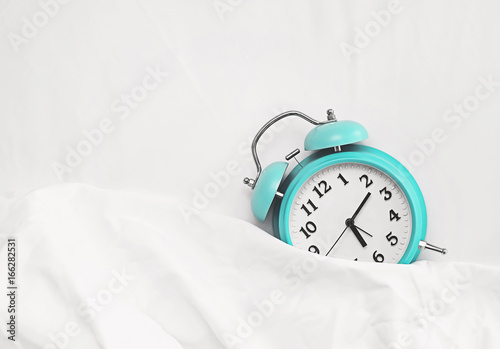 alarm clock on bed sheets