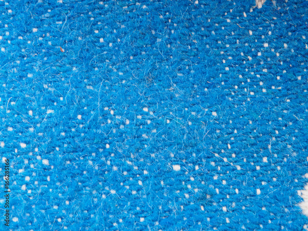A full page of blue synthetic faux material. Macro sweater, knitted wool texture. View of top on background texture. Braided wool texture closeup A full page of blue synthetic faux material. Macro sweater, knitted wool texture. View of top on background texture. Braided wool texture closeup