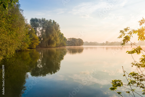 Fototapeta Naklejka Na Ścianę i Meble -  Pond with trees on a shores at sunrise