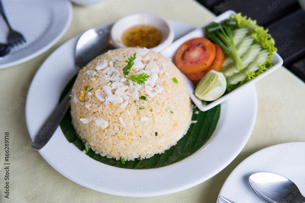 Crab fried rice with vegetables on white plate.