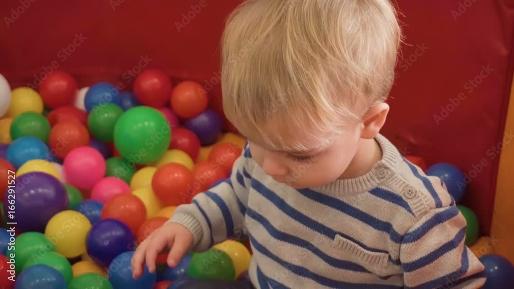 Little boy playing with lots of colorful plastic blocks, balls, kitchen in room Little boy playing with lots of colorful plastic blocks, balls, kitchen in room
