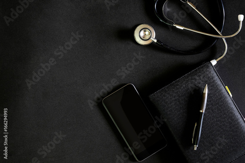 Dark leather modern doctor desk table with stethoscope and supplies.