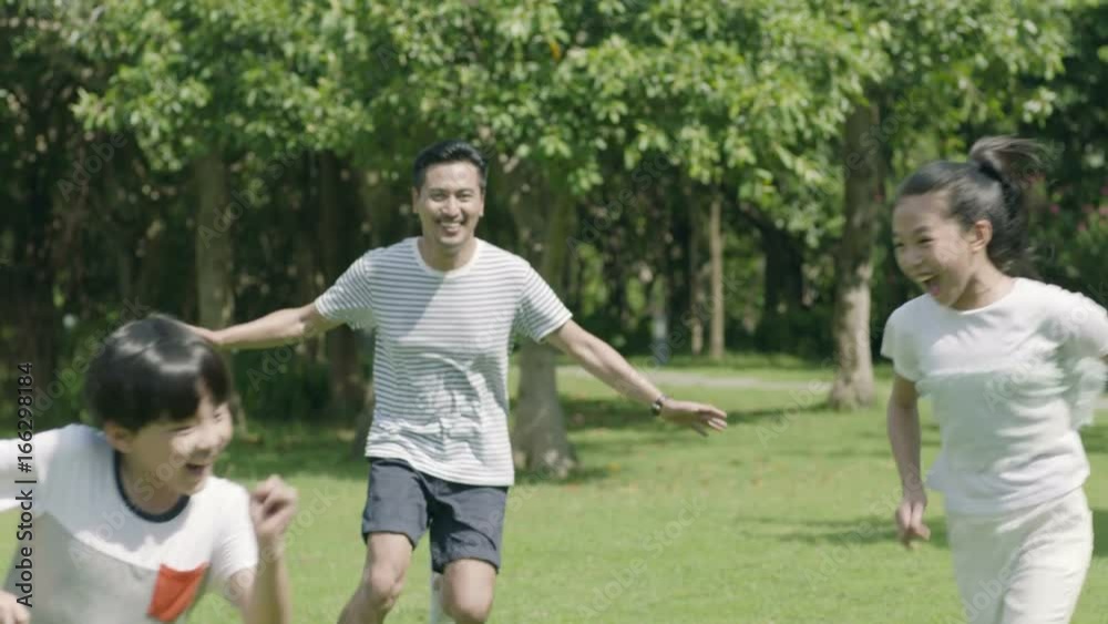 asian father playing chase game with his son & daughter in park in slow motion asian father playing chase game with his son & daughter in park in slow motion