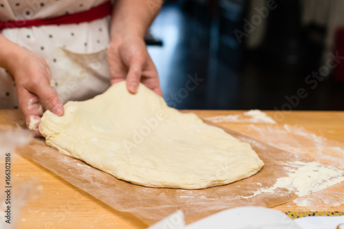 roll dough in flour on a wooden board, woman baker. Process of preparing pizza. Cooking time, cooking concept, selective focus