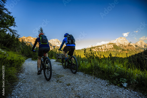 Mountain biking couple with bikes on track at sunset, Cortina d'Ampezzo, Dolomites, Italy