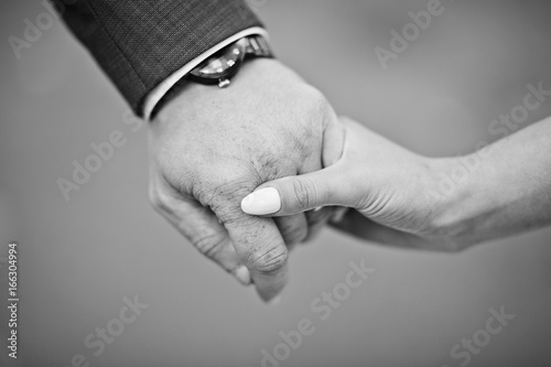 Groom holding bride's hand on the wedding day. Black and white photo.