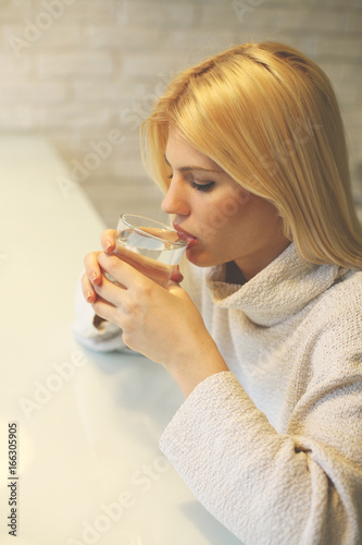 Portrait of young woman drinking water. Close-up portrait of beautiful blonde woman drinking water. Space for copy.