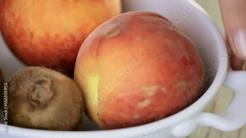 Slicing orgenic peach on wood cutting board photo