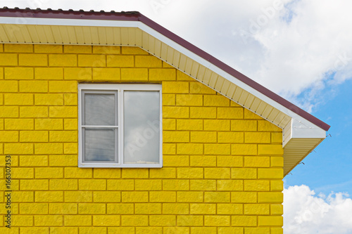 Painted yellow wall of blocks with a window