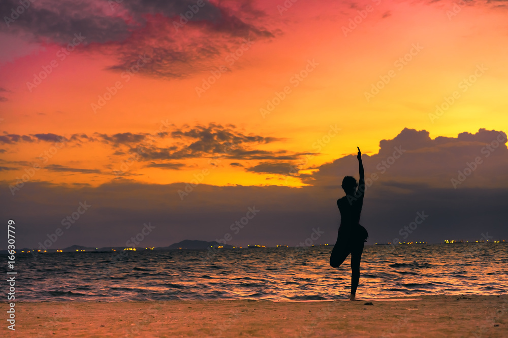 Young woman yoga exersice posting silhouette on the beach in summer