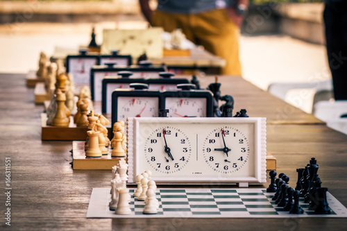 Variety of chess boards with chess pieces and chess clocks on wooden desk in due to the chess tournament photo