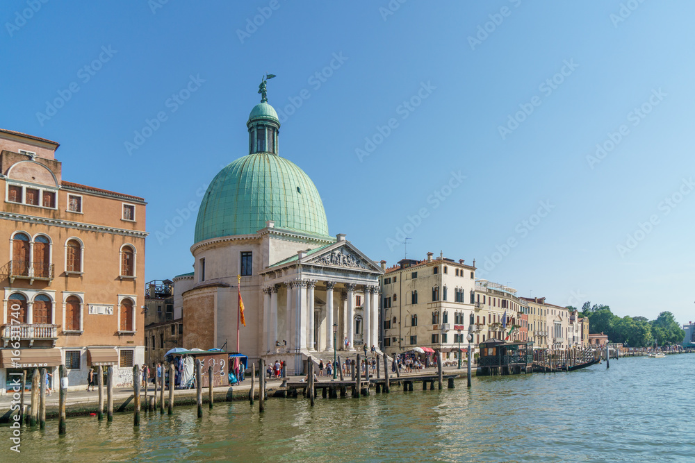 Venice with Grand canal, basilica, colorful buildings and walking tourists.
