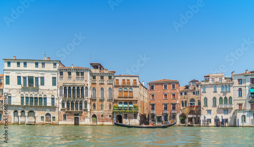 Venetian landscape with typical buildings, Grand canal and gondola at noon time.