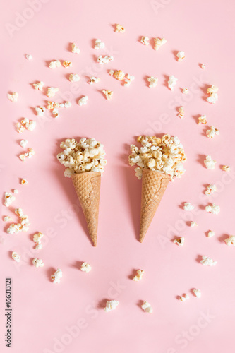 Popcorn in ice cream cones on pink background. Top view. Vertical.