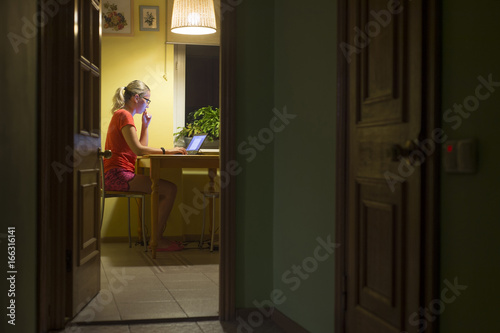 Woman working with laptop computer at night. Remote work. Work at home.