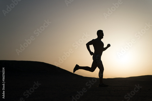 Fototapeta Naklejka Na Ścianę i Meble -  man running silhouette at sunset, young caucasian run in mountain