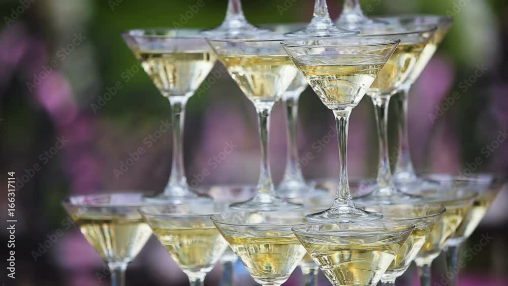 Pyramid from glasses of champagne on wedding party. Empty wine or champagne glasses on table are in pyramid. Tower of glasses at wedding ceremony outdoors Pyramid from glasses of champagne on wedding party. Empty wine or champagne glasses on table are in pyramid. Tower of glasses at wedding ceremony outdoors
