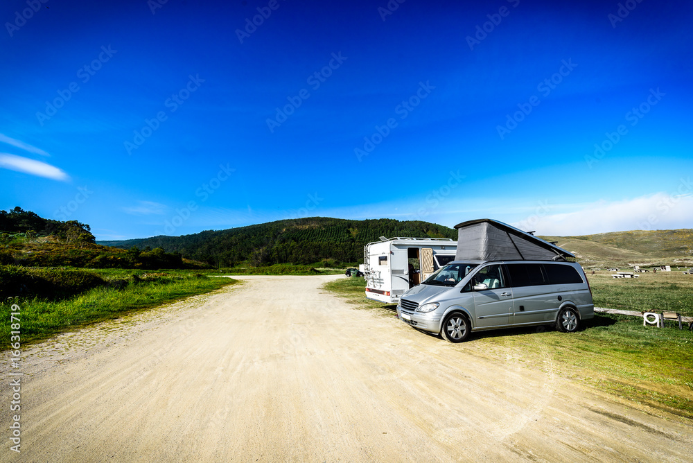 Motorhome RV and campervan are parked on a beach.