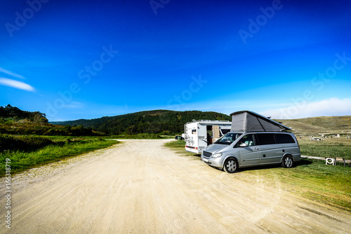 Motorhome RV and campervan are parked on a beach.