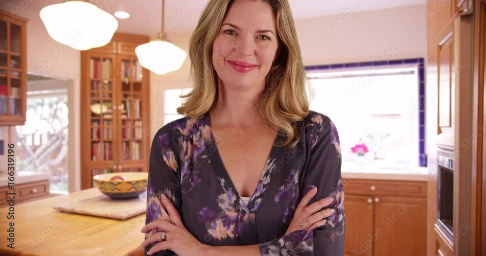 Portrait of woman in contemporary kitchen, smiling at camera with arms crossed Portrait of woman in contemporary kitchen, smiling at camera with arms crossed