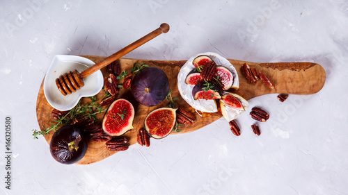 Cheese plate.Bree, camembert with fresh figs Honey, pecan and thyme. A snack on a wooden board.Top View.Copy space for Text.selective focus.