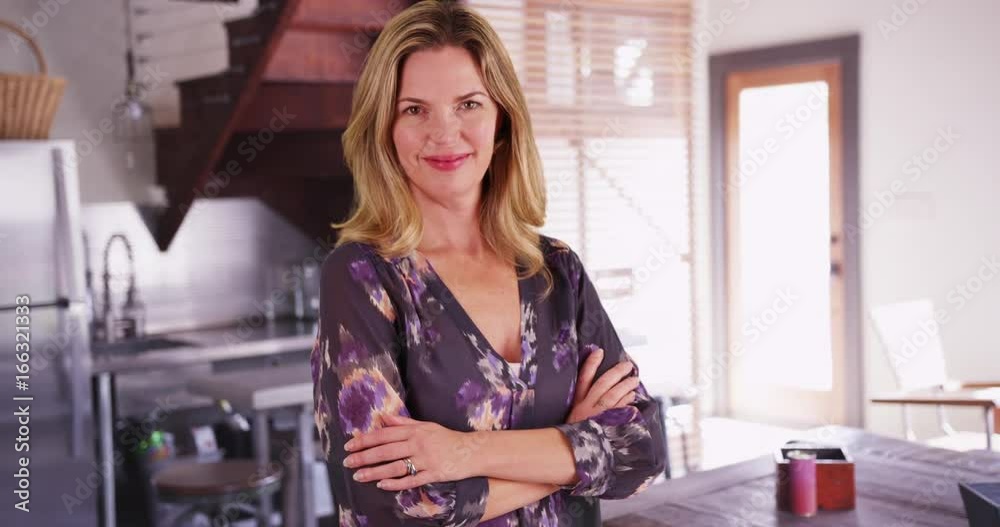 Portrait of woman in modern kitchen, smiling at camera with arms crossed Portrait of woman in modern kitchen, smiling at camera with arms crossed