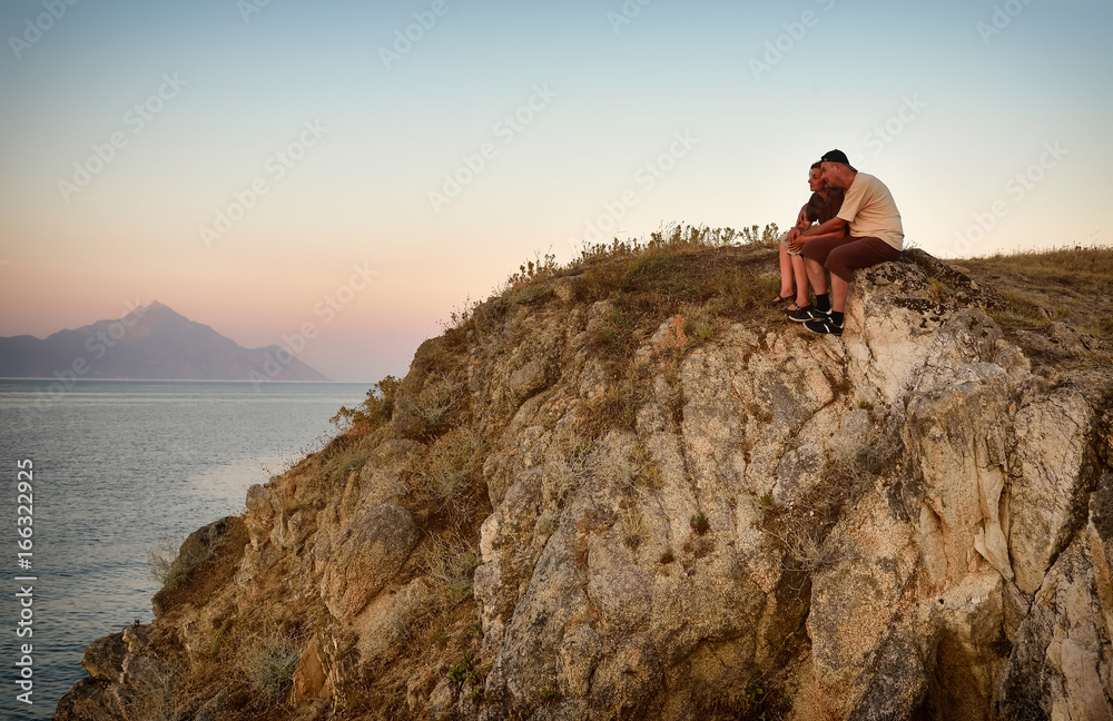 Couple in love sitting, hugging and enjoying on the top of the mountain in the sunset