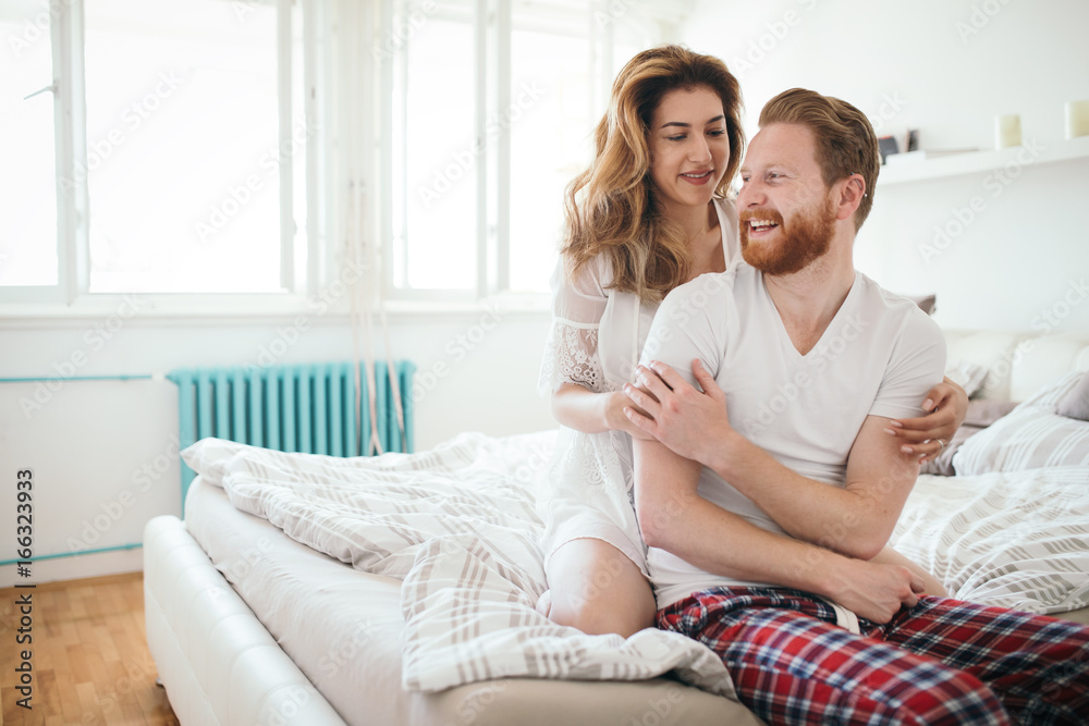 Beautiful happy couple waking up smiling in bedroom Beautiful happy couple waking up smiling in bedroom