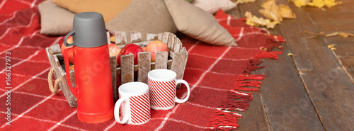 Autumn picnic on the terrace. Red plaid, basket with apples and thermos with hot drink. Veranda of countryside house in autumn season. Banner for website.