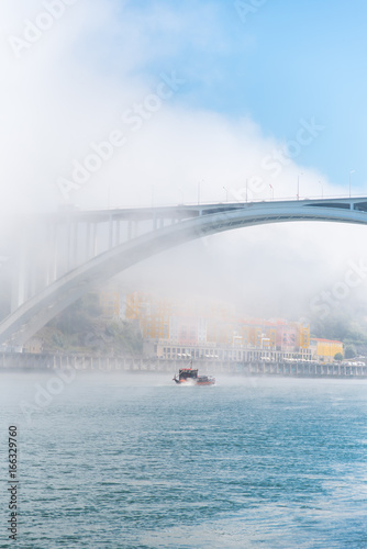 Porto in Portugal, Arrabida bridge, view of the Douro river in the mist, with a traditional boat 