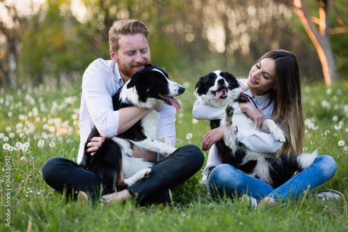 Romantic couple in love walking dogs in nature and smiling