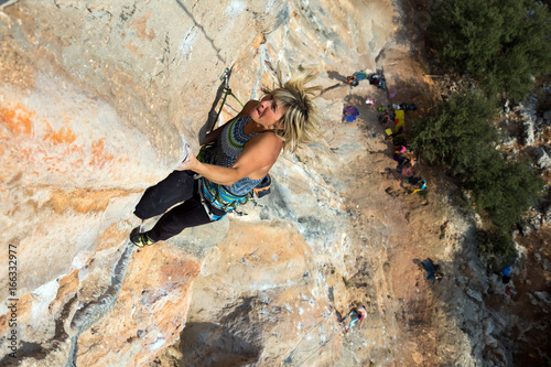 Female Rock Climber makes a difficult move on overhanging Wall