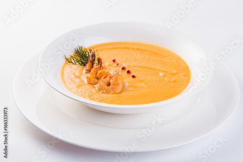 Fresh Creamy seafood soup with shrimps on a white plate on a light background (close)