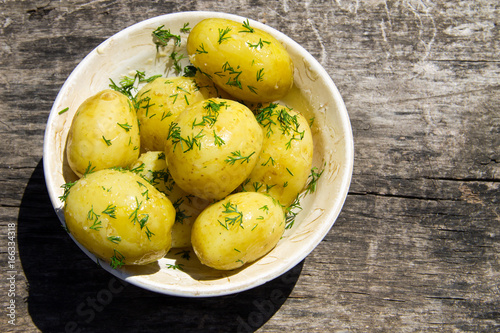 Boiled new potatoes with butter and dill on old wooden table. Top view