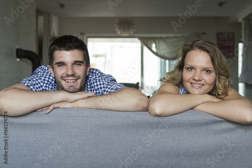 Portrait of smiling young couple at sofa in the living room photo