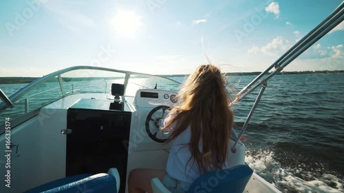 Summer vacation - young girl driving a motor boat