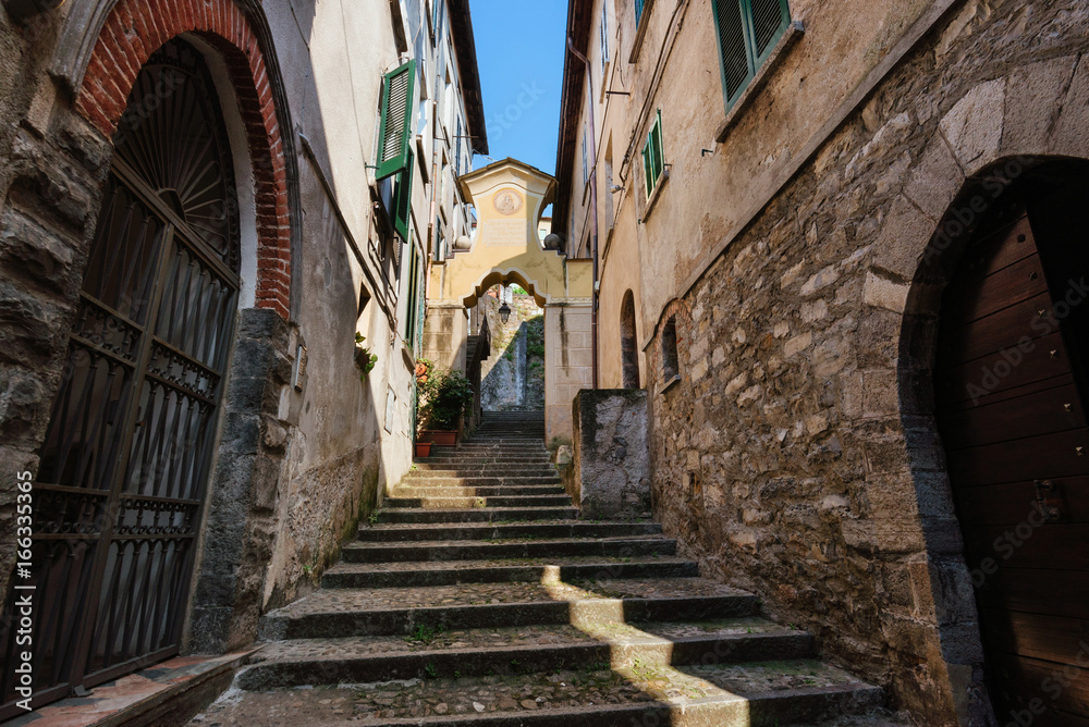 Narrow streets of authentic Bellano fishing village, situated on Como Lake shore. Traditional italian houses, stone steps and arcway  in small town Bellano, Lombardy, Italy.