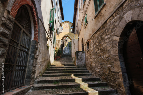 Fototapeta Naklejka Na Ścianę i Meble -  Narrow streets of authentic Bellano fishing village, situated on Como Lake shore. Traditional italian houses, stone steps and arcway  in small town Bellano, Lombardy, Italy.