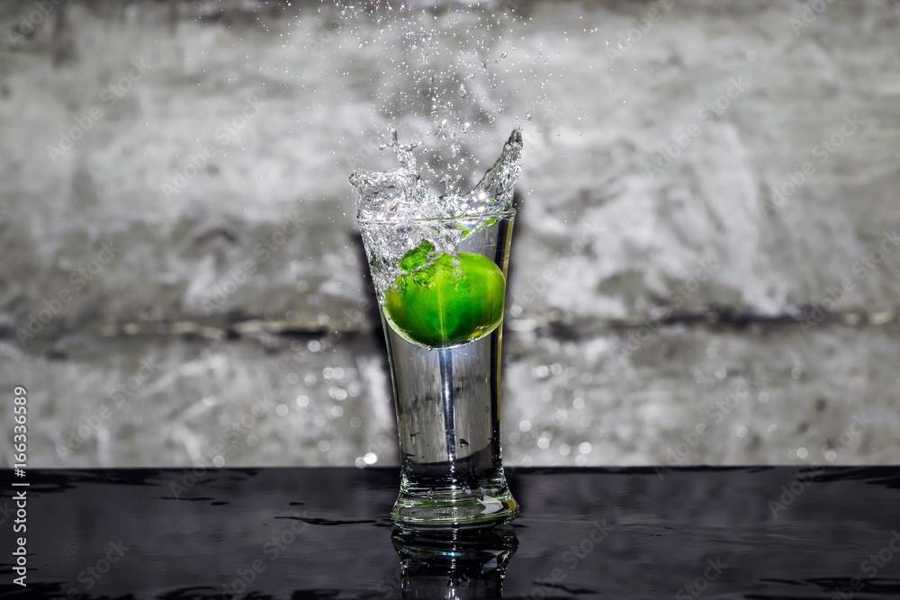 Throw lime into a glass of water, splashing water over glass. Throw lime into a glass of water, splashing water over glass.