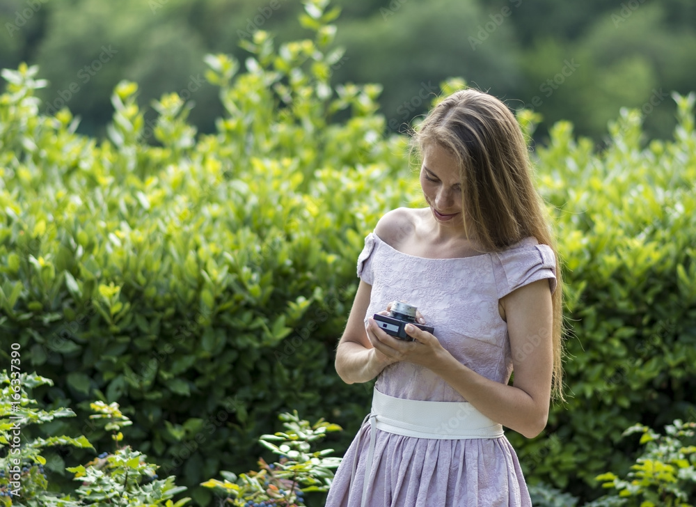 Beautiful woman is holding old fashioned camera in hand, outdoors. Beautiful woman is holding old fashioned camera in hand, outdoors.